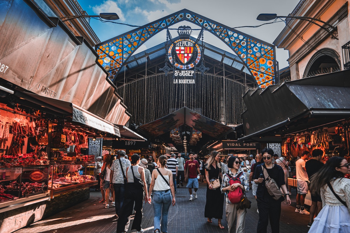 Crowds under the modernista stained-glass entrance arch of La Boquería market on Las Ramblas